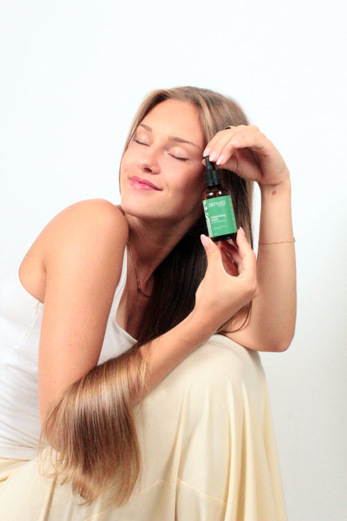 Woman holding a Zenvia hair oil bottle with a white background